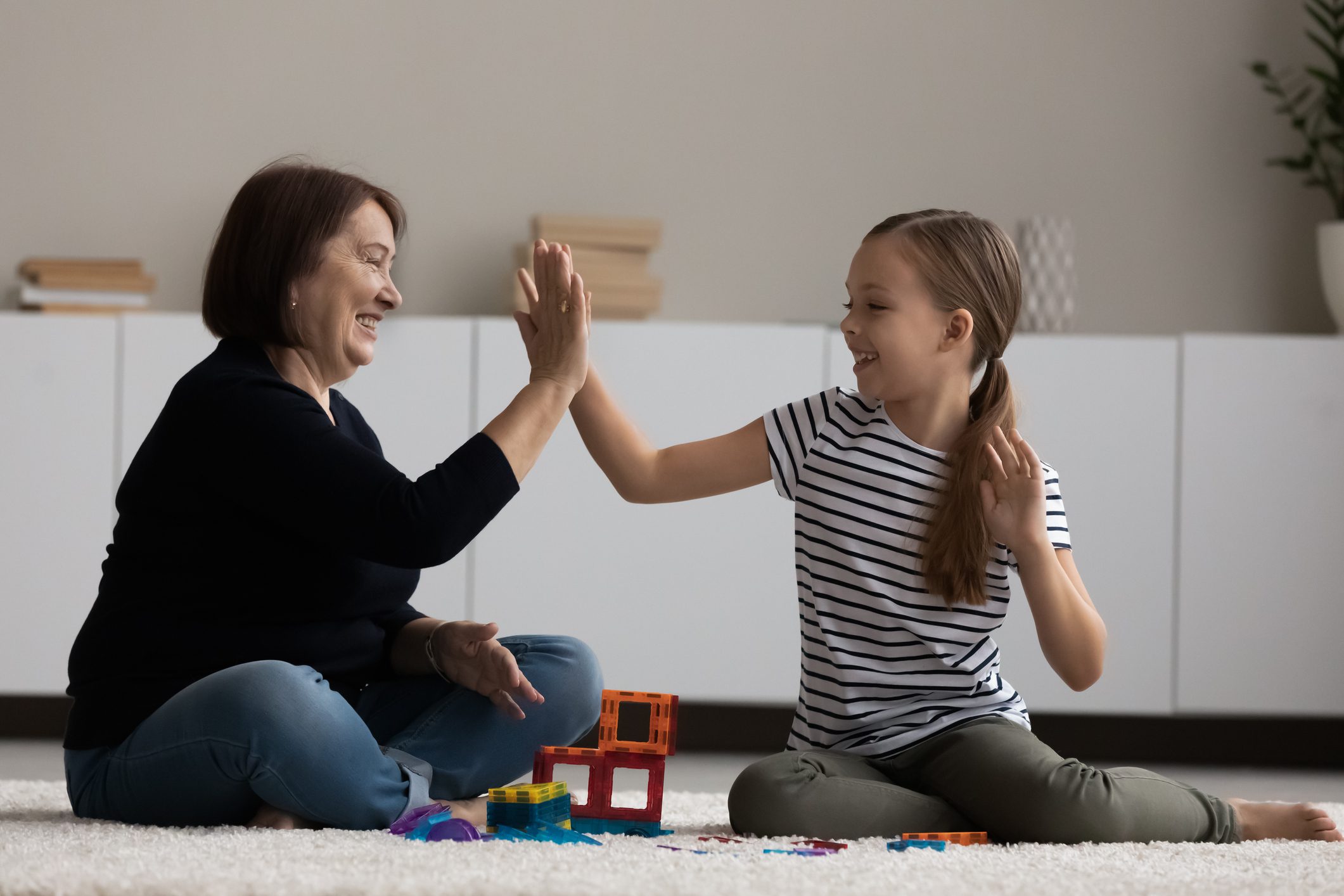 Happy young granny playing with small kid girl.